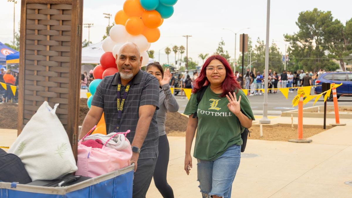 student and family waving while pushing move in carts